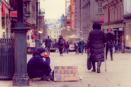 OSLO, NORWAY - MARCH, 26, 2018: Outdoor view of unidentified homeless man sitting in the ground asking for money in the streets of Oslo townのeditorial素材