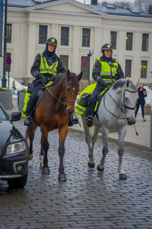 OSLO, NORWAY - MARCH, 26, 2018: Outdoor view of police on horse in Oslo city, close to unidentified people walking in the sreetsのeditorial素材