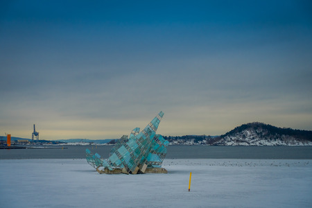 OSLO, NORWAY - MARCH, 26, 2018: Outdoor view of the city and glass structure art in the middle of the frozen river, located in Oslo, Norwayのeditorial素材