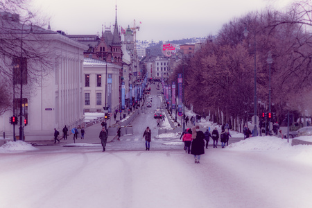 OSLO, NORWAY - MARCH, 26, 2018: Outdoor view of unidentified people walking in the streets surrounding of trees covered with snow in Oslo townのeditorial素材