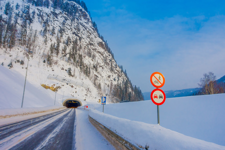 Reinli, Norway - March 26, 2018: Outdoor view of winter road snow and ice in the forest, with informative sign at the enter of a tunnel in Norwayのeditorial素材