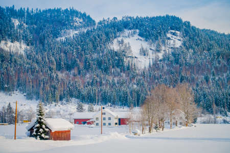Astonishing outdoor view of traditional Norwegian mountain red houses of wood covered with snow in the roof in stunning nature mountain background in Norwayの写真素材