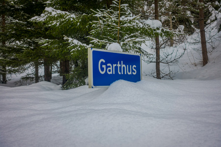 Reinli, Norway - March 26, 2018: Outdoor view of sign of Garthus at one side during winter in the road, almost covered with snow and ice in the forestのeditorial素材