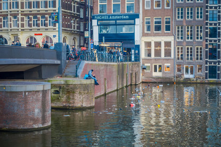 AMSTERDAM, NETHERLANDS, MARCH, 10 2018: Beautiful outdoor view of apartment buildings with abridge over a canal in the city of Amsterdamのeditorial素材