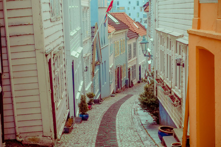 BERGEN, NORWAY - APRIL 03, 2018: Narrow Small stone medieval street in the Bergen City, Norway, with the old white wooden house on the side of the road, typical stone roadのeditorial素材