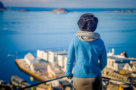 Unidentified woman enyoing the view of Alesund port town on the west coast of Norway, at the entrance to the Geirangerfjordの写真素材