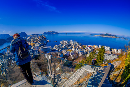 ALESUND, NORWAY - APRIL 04, 2018: Unidentified woman enjoting the view from the birds eye view of Alesund port town on the west coast of Norway, at the entrance to the Geirangerfjordのeditorial素材