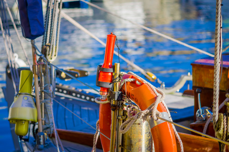 ALESUND, NORWAY - APRIL 04, 2018: Outdoor view of ropes around a lifesaver of color oragnge in the city of Alesund with tour boat and old sail boatのeditorial素材
