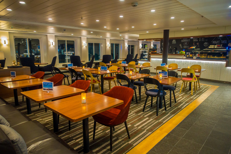 ALESUND, NORWAY - APRIL 04, 2018: Indoor view of dinning tables with confortable chairs with candles inside of Hurtigruten voyage in cruiseのeditorial素材