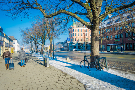 TRONDHEIM, NORWAY - APRIL 04, 2018: Outdoor view of unidentified people walking in the streets with traditional Scandinavian buildings stand along in Trondheimのeditorial素材