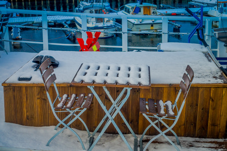 Bodo, Norway - April 09, 2018: Outdoor view of mixed mettalic and wooden chair at outdoors covered with snow in the marina port area in Bodoのeditorial素材
