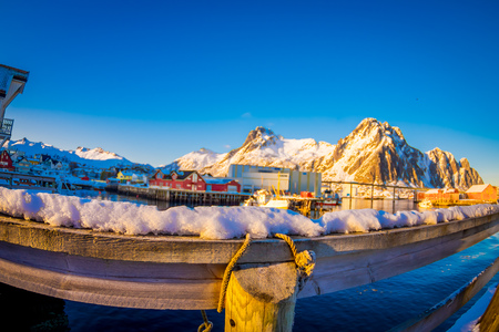 SVOLVAER, LOFOTEN ISLANDS, NORWAY - APRIL 10, 2018: Close up of rope around a wood stick covered with snow Outdoor view of harbor houses in Svolvaer, with a boat in the shore, located in the island of Austvagoya in Lofotenのeditorial素材