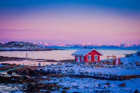 SVOLVAER, LOFOTEN ISLANDS, NORWAY - APRIL 10, 2018: Outdoor view of pink sky with red rorbu fishing building on a rock in Lofoten Islands, Svolvaerのeditorial素材