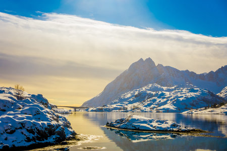Beautiful outdoor view of mountain and reflection in water with a Gimsoystraumen Bridge in the...
