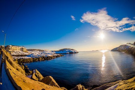Outdoor view of clear water with a sun reflecting in the lake in the bay of Lofoten Islandsの写真素材