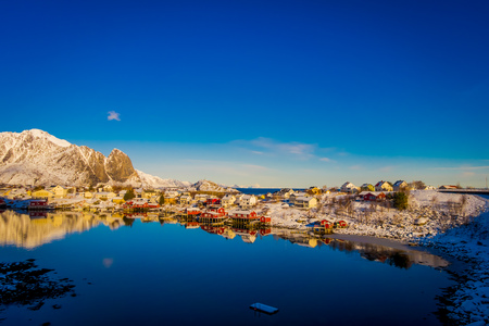 Henningsvaer, Norway - April 09, 2018: Beautiful above view of wooden buildings with huge mountaing behind in Henningsvaer in Lofoten islandsのeditorial素材