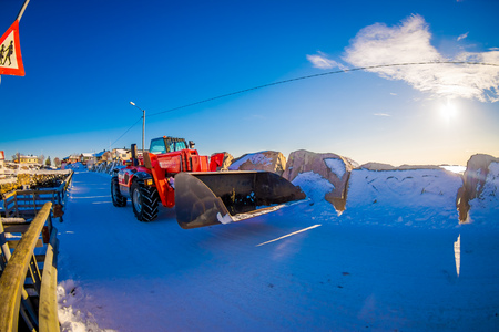 HENNINGSVAER, NORWAY - APRIL 10, 2018: Outdoor view of red tractor covered with snow on a sunny day during wniter in a blue skyのeditorial素材