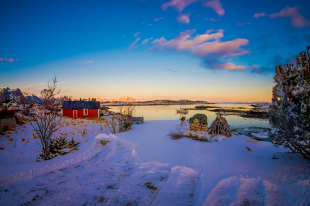 Outdoor view of blurred picture with metallic structure standing over the snow in a gorgeous sunset with a pile of timber or trunks in the snow on a frozen lake in the horizontの写真素材