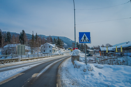 GOL, NORWAR, APRIL, 02, 2018: View of cleaned road and some cars parked at one side, with an informative sigh in the street covered with snow in GOLのeditorial素材
