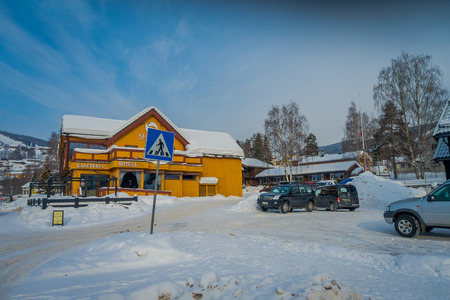 GOL, NORWAR, APRIL, 02, 2018: Outdoor view of yellow wooden building covered with snow and some cars parked in the parking area in GOLのeditorial素材