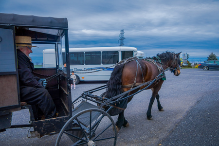 Pennsylvania, USA, APRIL, 18, 2018: Outdoor view of unidentified man driving an Amish buggy carriage in the streets with other cars in a roadのeditorial素材