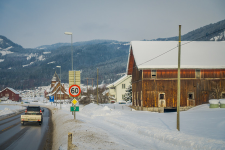 GOL, NORWAR, APRIL, 02, 2018: View of wooden building located at one side of the road with a car in the road covered with snow in GOLのeditorial素材
