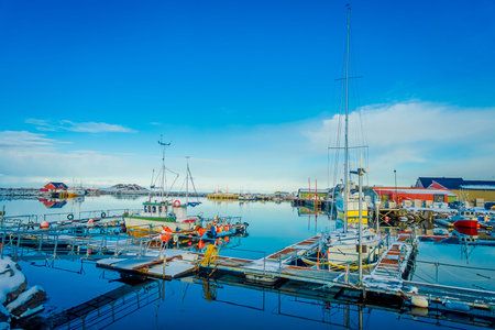 Henningsvaer, Norway - April 04, 2018: Outdoor view of fishing port in Henningsvaer with typical red wooden buildings and small fishing boats on Lofoten islandsのeditorial素材
