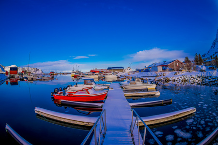 SVOLVAER, LOFOTEN ISLANDS, NORWAY - APRIL 10, 2018: View of red fishing boats in harbour with buildings in the horizont in a gorgeous blue sky and sunny day, Svolvaer, Lofoten Islandsのeditorial素材