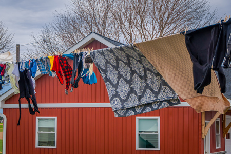 Outdoor view of clothes of Amish drying in the sun and air after laundry with a wooden red house background in Lancasterの写真素材