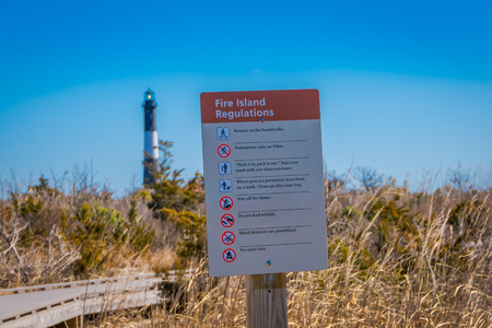 LONG ISLAND, USA, APRIL, 04, 2018: Outdoor view of informative sign of fire island regulations with some tips located at outdoors of the beach with Montauk Lighthouse behind at Long islandのeditorial素材