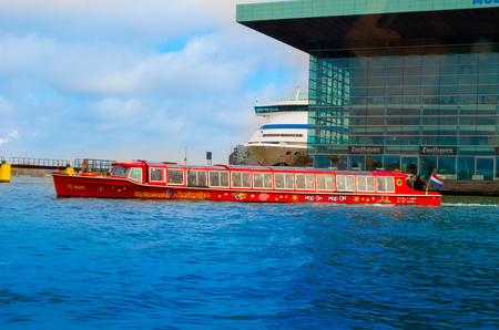 AMSTERDAM, NETHERLANDS, APRIL, 23 2018: Outdoor view of red boat in a shore of the canal is the capital and most populous city of the Netherlands with a building infraestructure behindのeditorial素材