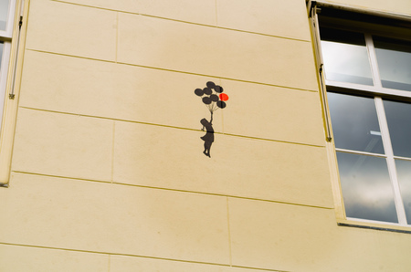 AMSTERDAM, NETHERLANDS, APRIL, 23 2018: Outdoor view of figure of little girl with ballons in her hands over the wall of a building of the street in dowtownのeditorial素材