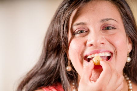 Portrait of woman wearing a pink blouse and eating a star gooseberry fruit. Phyllanthus acidus,...