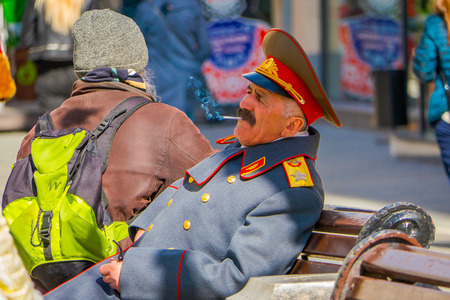 MOSCOW, RUSSIA- APRIL, 24, 2018: View of unidentified man wearing uniform and smoking a cigarette at outdoors sitting in a public chairon Nikolskaya streetsのeditorial素材