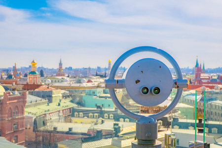 Close up of metallic structure of coin operated binocular with city behind of Moscow business...