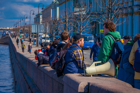 ST. PETERSBURG, RUSSIA, 01 MAY 2018: Outdoor view of unidentified people sitting in a border at the riverside close to a white megaphone in St. Petersburgのeditorial素材
