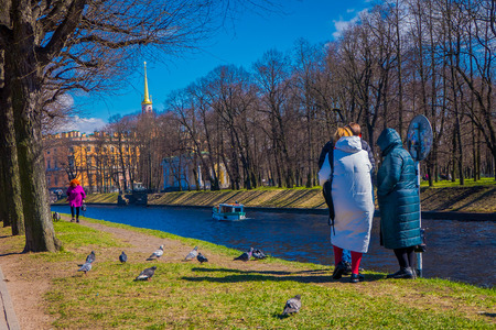 ST. PETERSBURG, RUSSIA, 02 MAY 2018: Outdoor view of unidentified people in a park having a good time with their relatives in the border of the Moika river in a sunny day in St Petersburgのeditorial素材