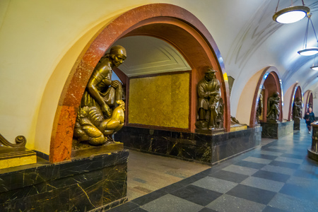 MOSCOW, RUSSIA- APRIL, 29, 2018: Tourist walking in a subway metro station in Ploshchad Revolyutsii, with a gorgeous bronze sculpturin the corner of the arch inside the building in Moscowのeditorial素材