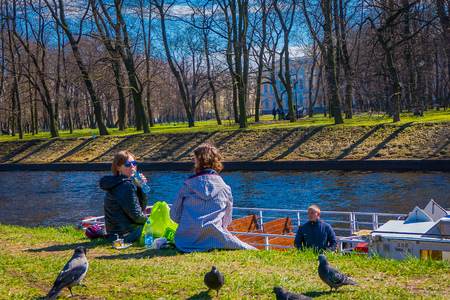 ST. PETERSBURG, RUSSIA, 02 MAY 2018: Outdoor view of unidentified people in a park having a good time with their relatives in the border of the Moika river in a sunny day in St Petersburgのeditorial素材