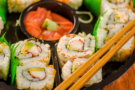 Close up of selective focus of large set of delicious japanese sushi rolls on a black plastic plateの写真素材