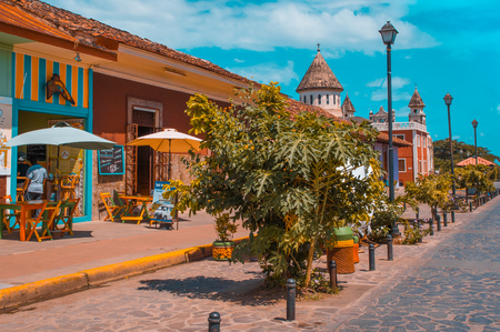 GRANADA, NICARAGUA - APRIL 28, 2016: Outdoor view of restaurants in a colonial and beautiful colorful buildings in a row in the city with some unbrella chairs for tourist to eatのeditorial素材