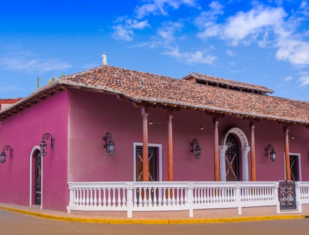 GRANADA, NICARAGUA, MAY, 14, 2018: Outdoor view of facade buildings with pink wall, wooden door and roof in a gorgeous blue sky background in the historic city center of Granadaのeditorial素材
