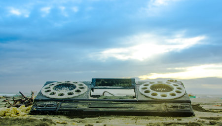 Close up of plastic piece of an old radio, over the sand in the beach