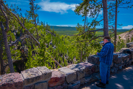 YELLOWSTONE, MONTANA, USA MAY 24, 2018: Unidentified man using his camera to record the view of river plunging down into the grand canyon of Yellowstone National Parkのeditorial素材