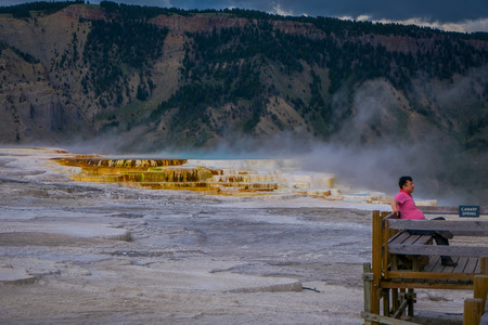 YELLOWSTONE, MONTANA, USA MAY 24, 2018: Unidentified man sitting in a chair in front of Canary Springs on terraces of Mammoth Hot Springs in Yellowstone National Park, Wyomingのeditorial素材