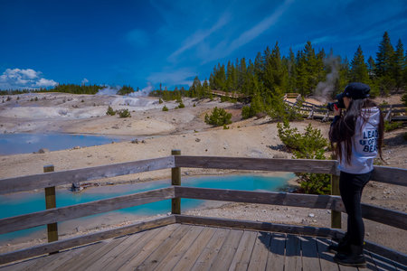 YELLOWSTONE, MONTANA, USA JUNE 02, 2018: Unidentified woman taking pictures and enjoying the view of pools of colorfully colored water dot of the Norris Geyser Basin in Yellowstone National Parkのeditorial素材
