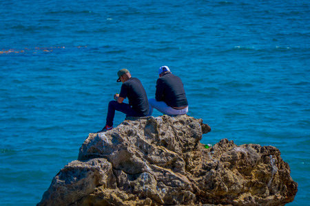 Los Angeles, California, USA, JUNE, 15, 2018: Outdoor view of unidentified friends talking and sitting over a rock in the beach of Malibu Californiaのeditorial素材