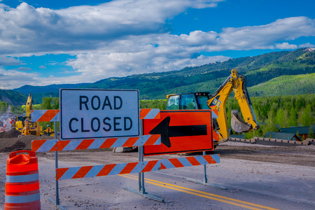 YELLOWSTONE NATIONAL PARK, WYOMING, USA - JUNE 07, 2018: Informative sign of road closed with equipment parked in a construction zone in Yellowstone National Parkのeditorial素材