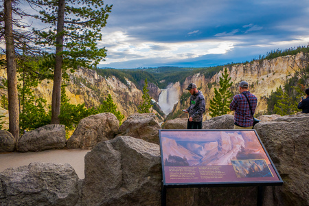 YELLOWSTONE NATIONAL PARK, WYOMING, USA - JUNE 07, 2018: Outdoor view of informative sign with tousits using their devices to take pictures of the landscape in Yellowstone National Park, Wyoming in USのeditorial素材