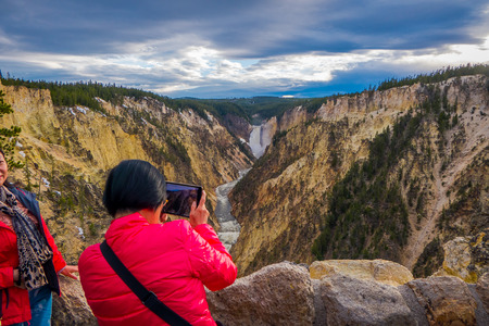 YELLOWSTONE NATIONAL PARK, WYOMING, USA - JUNE 07, 2018: Unidentified tourists taking pictures of the beautiful upper fall in Yellowstone National Park, Wyomingのeditorial素材
